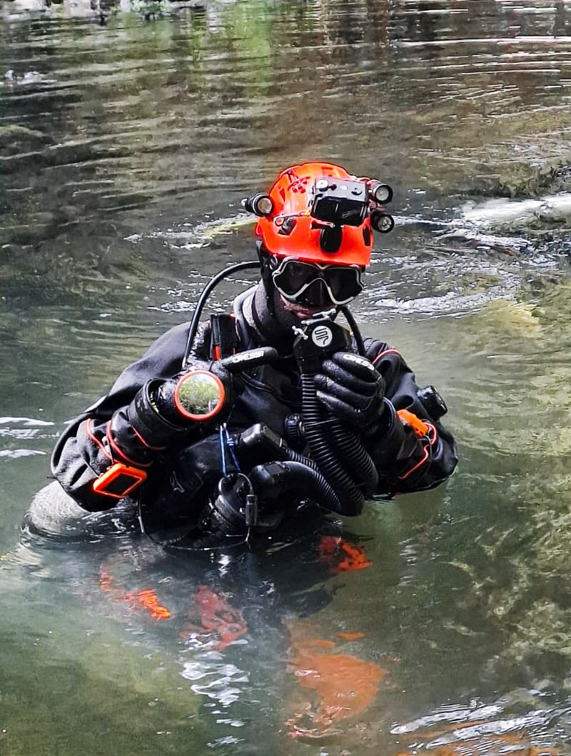Portrait in a drysuit with helmet and lights in the water